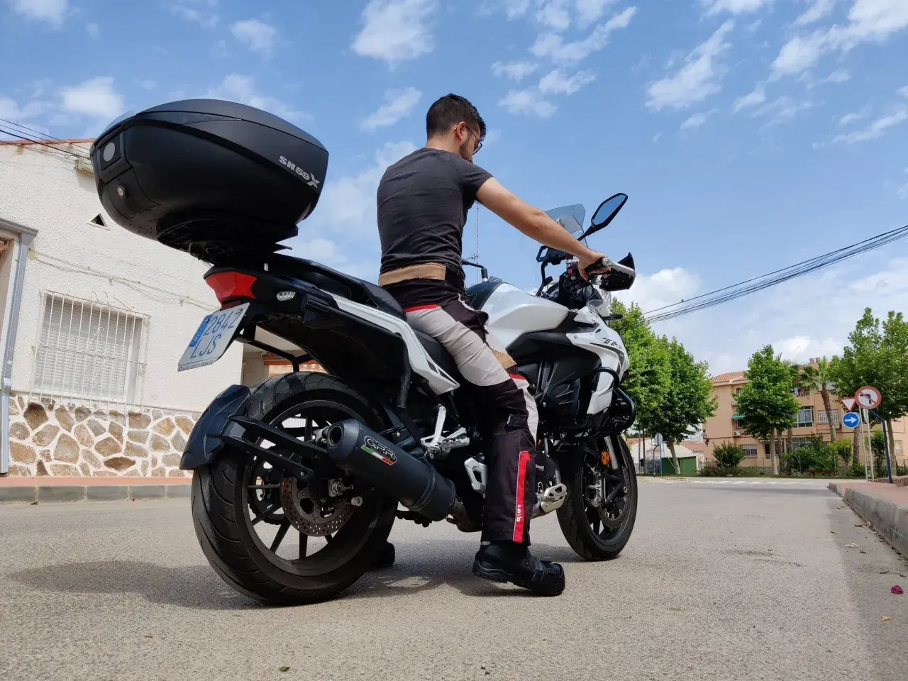 Hombre sentado en una Benelli TRK 502, mostrando la altura del asiento. La moto tiene un baúl SH59X.