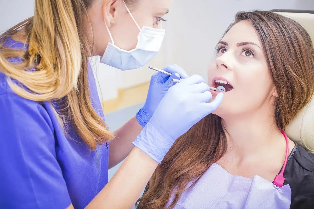 Dentystka bada jamę ustną pacjentki, szukając ewentualnych zmian.