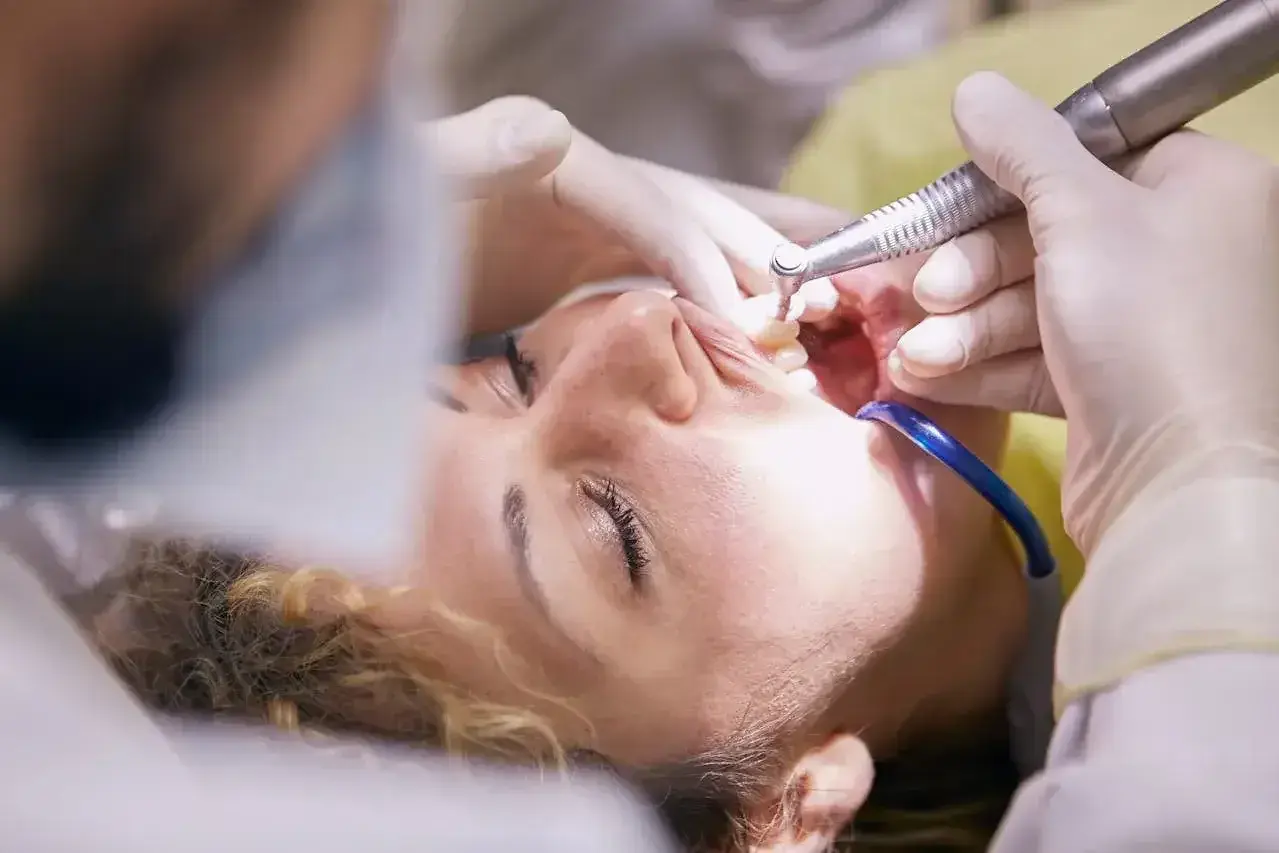 Pacjentka u dentysty, trwa zabieg. Czy leczenie kanałowe jest na NFZ? Warto sprawdzić, bo czasem można zaoszczędzić.