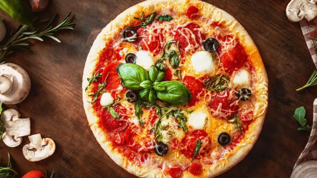 Leckere Pizza mit Salami, Mozzarella und Oliven auf einem Holzbrett. Ein schneller Pizzateig ohne Hefe macht sie im Handumdrehen fertig.
