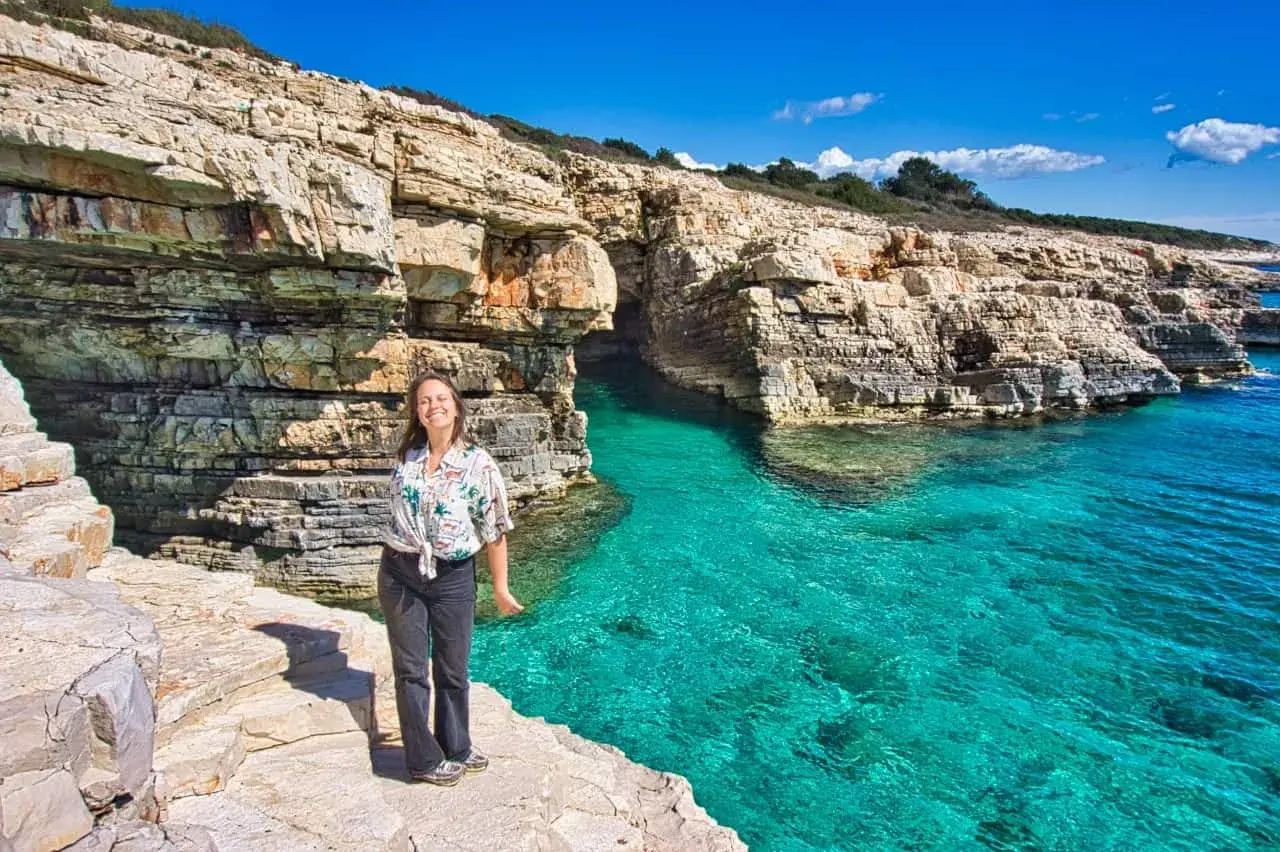Frau genießt die Sonne an einer felsigen Küste mit türkisfarbenem Wasser. Perfekte pula unternehmungen für einen Urlaub.