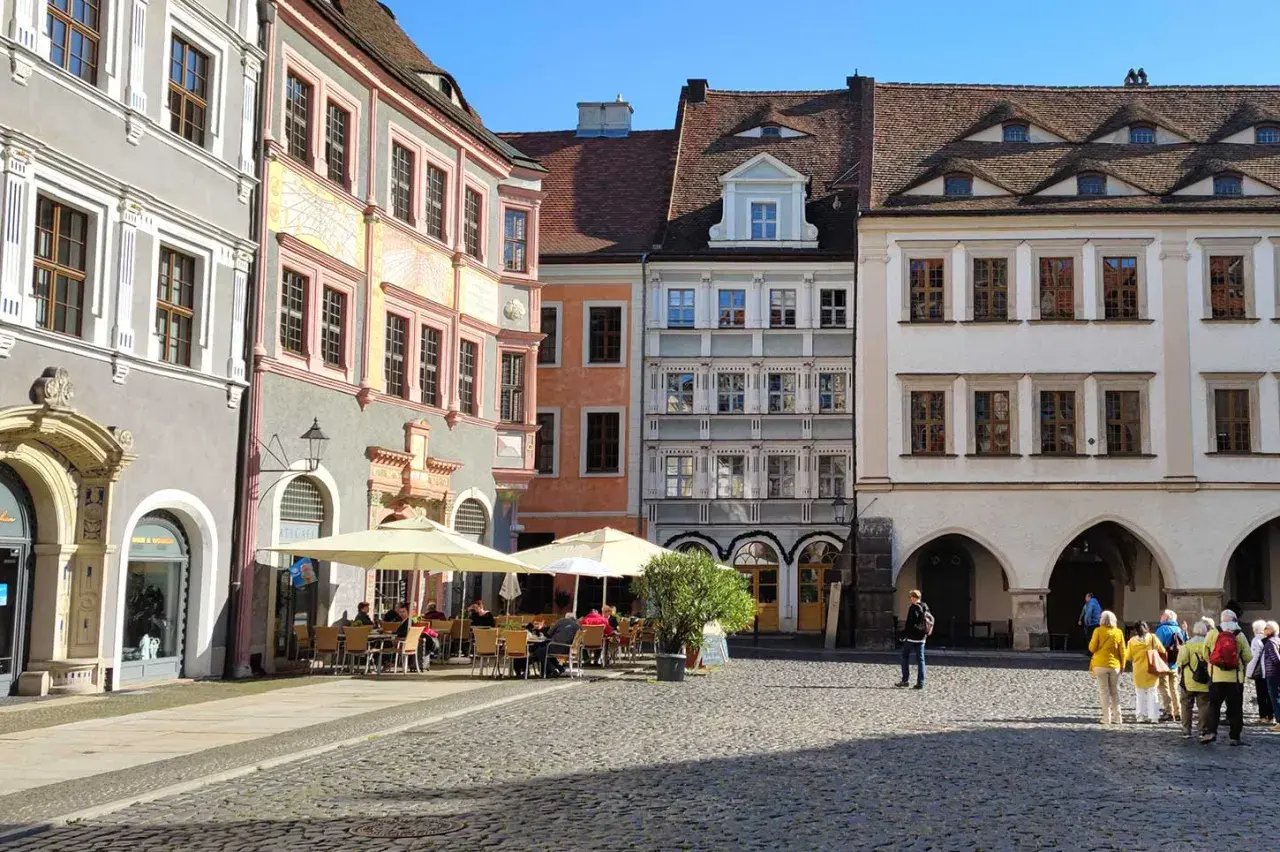 Café mit Außenbestuhlung auf einem historischen Platz mit bunten Häusern.