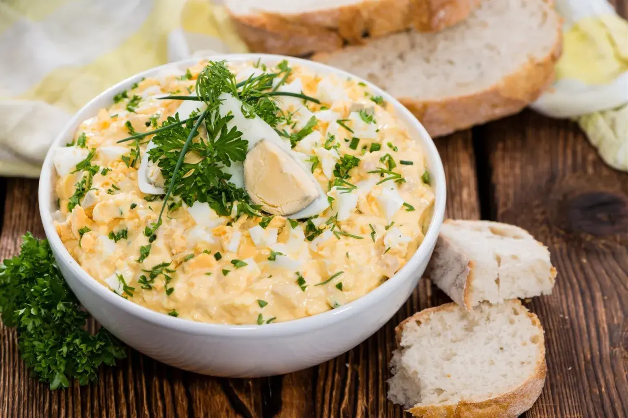 Pyszna pasta z jajek, udekorowana natką pietruszki i jajkiem na twardo, podana z chlebem.