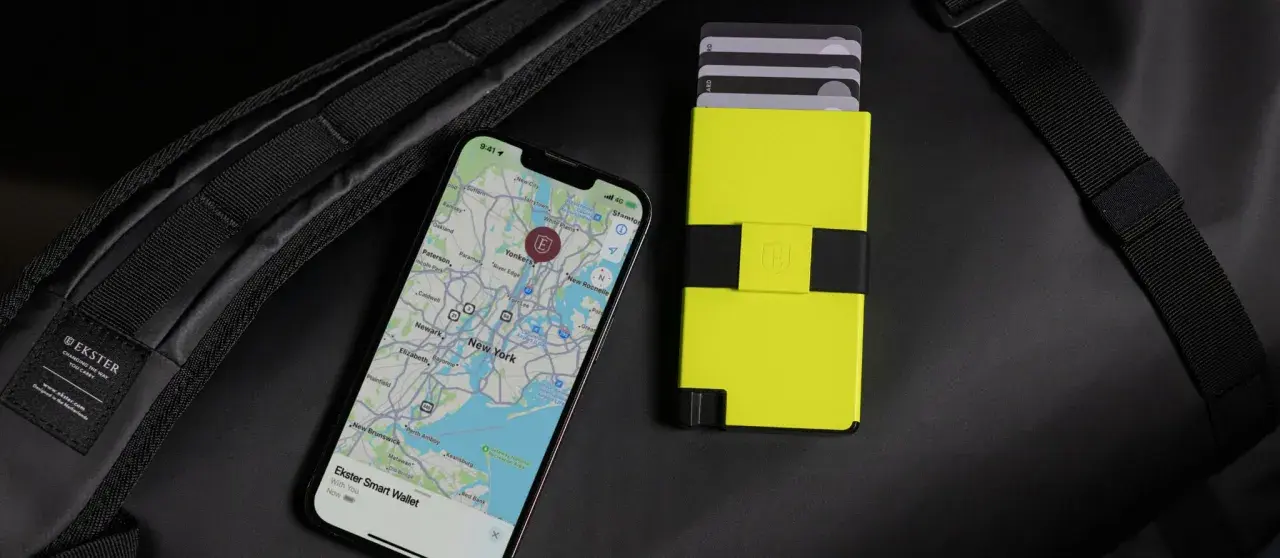 Ein Smartphone mit Karte von New York und ein gelbes Kartenetui liegen neben einem schwarzen Rucksack. Perfekt, um bargeldlos zu bezahlen.