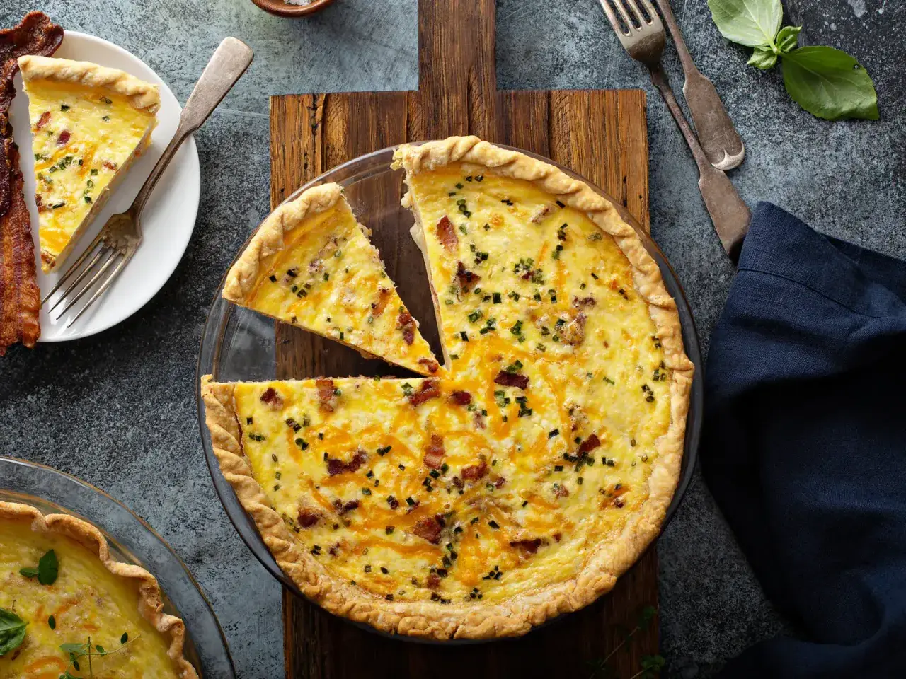 Une quiche au bacon et fromage, parfaite pour une recette quiche facile. Une part est déjà servie avec du bacon croustillant.