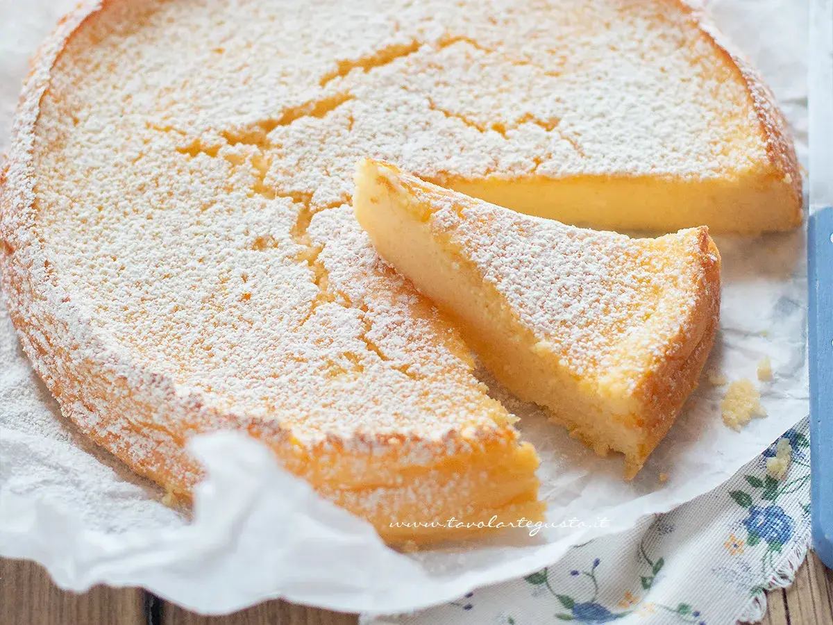 Deliziosa torta ricotta e limone, soffice e spolverata di zucchero a velo, con una fetta tagliata.