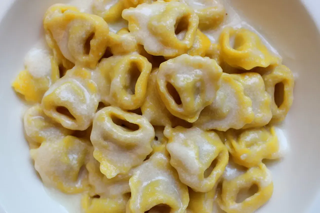 Tortellini freschi immersi in una cremosa fonduta di parmigiano, un abbraccio di sapore.