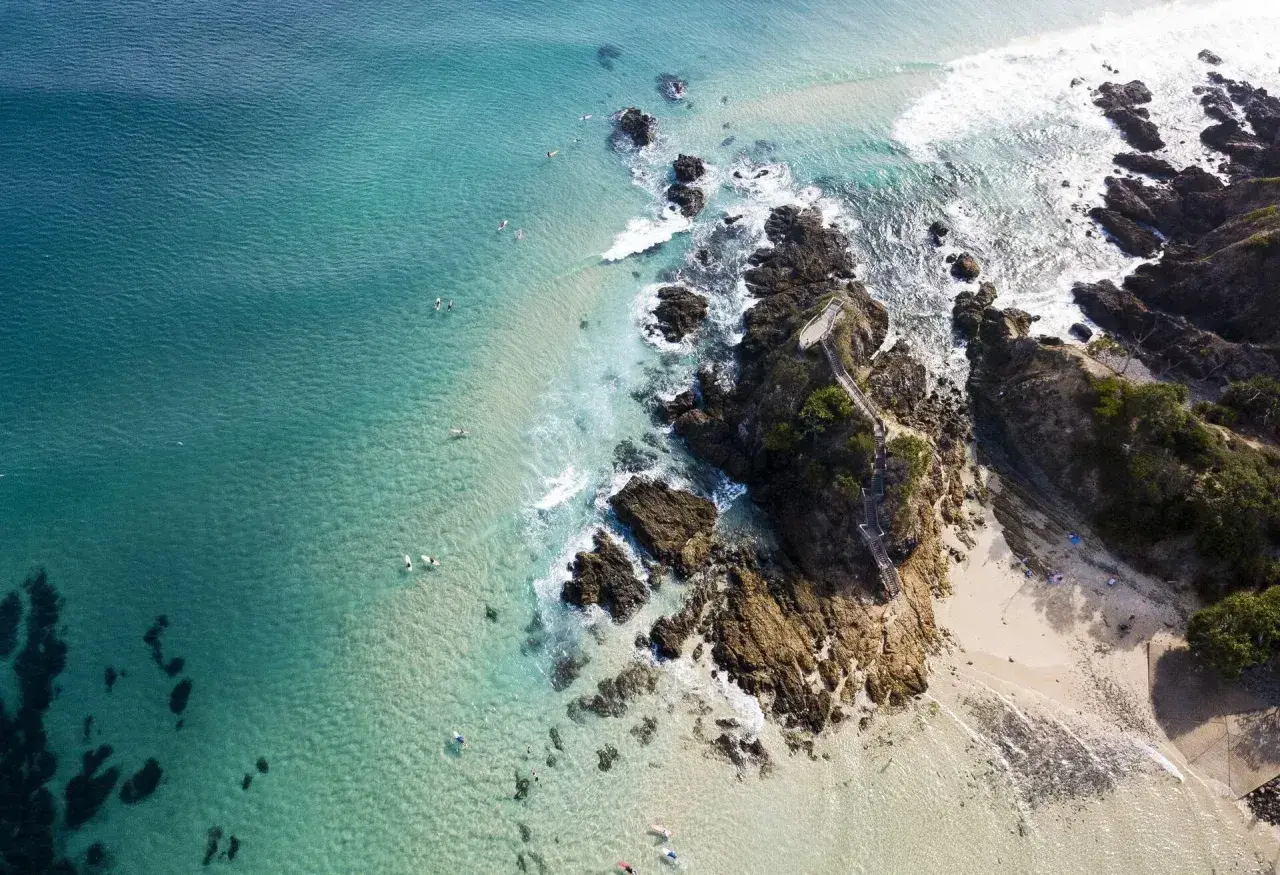 Türkisblaues Meer, Surfer und felsige Küsten – ein Bild von traum reiseziele, das zum Träumen einlädt.