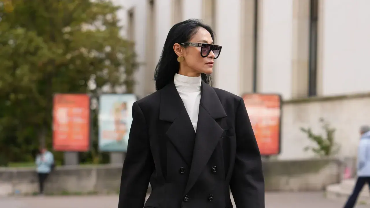 Stilvolles Outfit: Schwarzer Blazer über einem weißen Hemd mit Rollkragen kombinieren. Modische Sonnenbrille und goldene Ohrringe runden den Look ab.