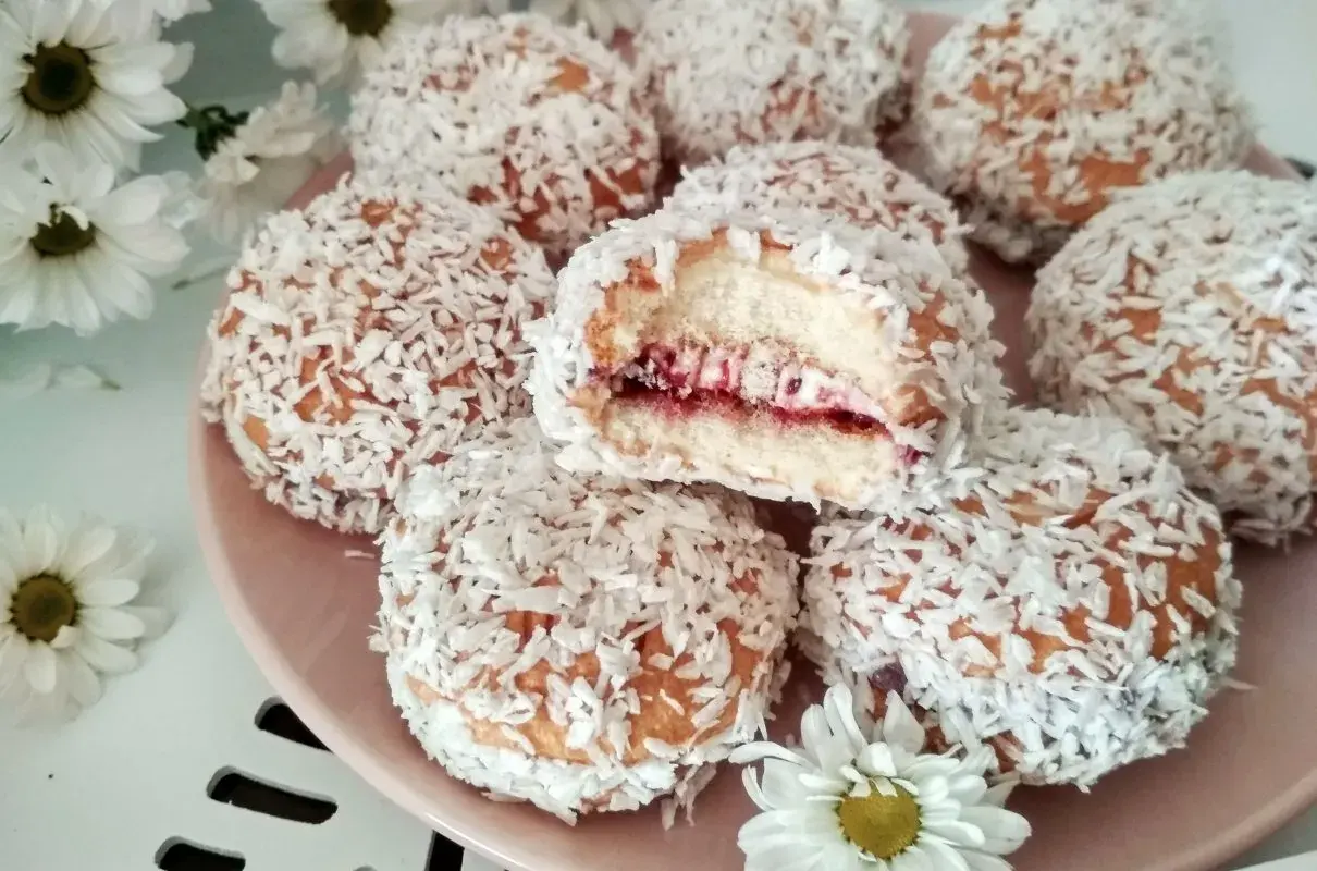 Pyszne ciastka biszkoptowe z nadzieniem owocowym i wiórkami kokosowymi, wyglądają jak małe śnieżne kuleczki.