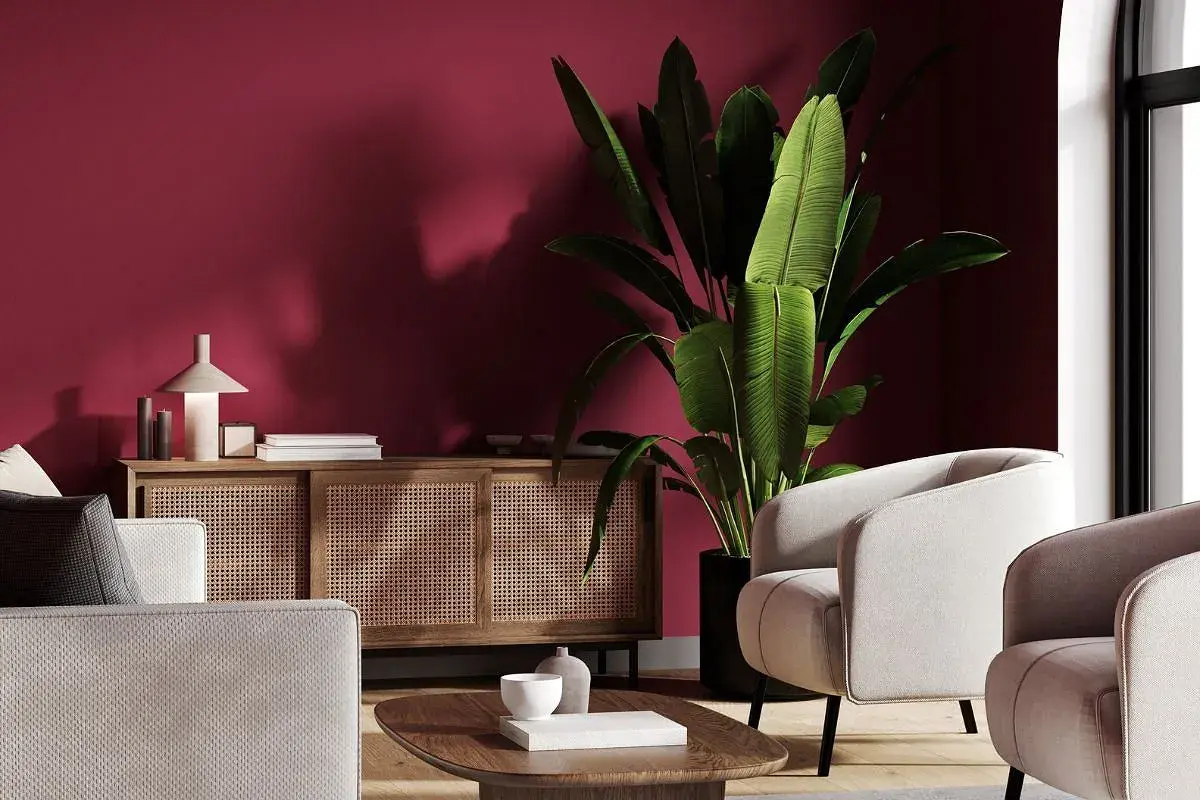 Elegancki salon z dominującym kolorem burgund. Jasne meble i drewniana komoda z rattanem tworzą przytulną atmosferę.