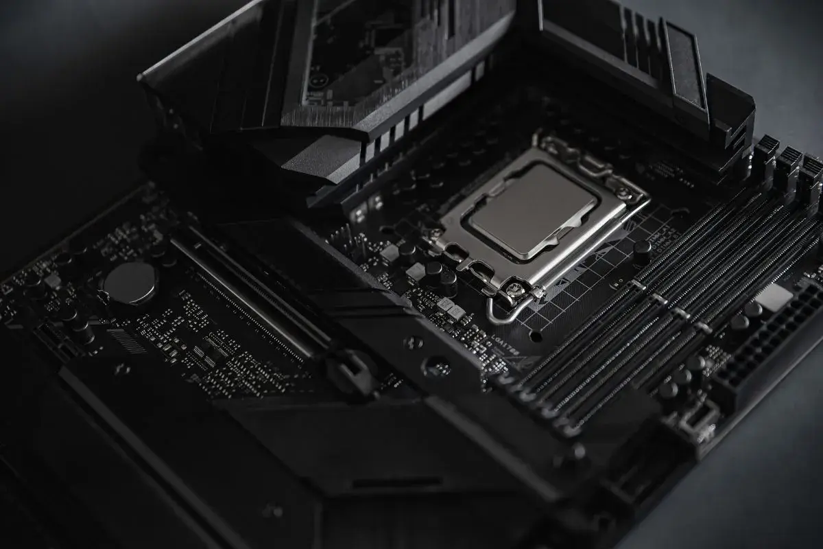 Czarna płyta główna z procesorem i slotami RAM. Widoczny radiator i elementy chipsetu.