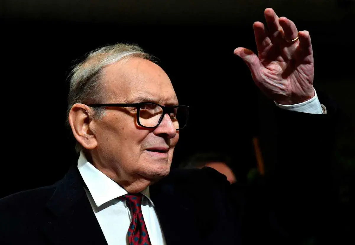 Ennio Morricone, kompositören bakom ikoniska filmer, vinkar med en ring på fingret.