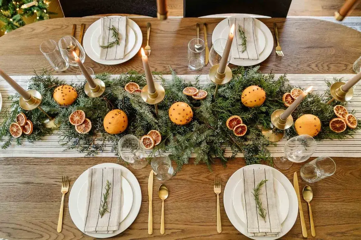 Vackert dukat julbord med granris, apelsiner med nejlikor, torkade apelsinskivor och ljus. En perfekt inspiration för att dekorera julbordet.
