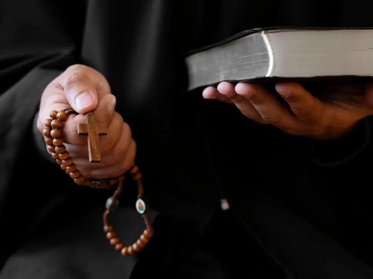 Ein Priester hält ein Rosenkranz und eine Bibel. Dies sind Werkzeuge, die bei einem Exorzismus verwendet werden, um böse Geister zu vertreiben.