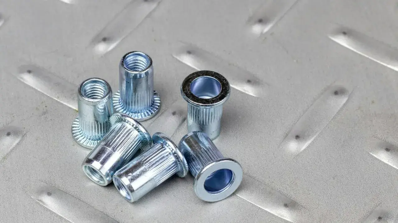 Kilka metalowych nitotrzpieni leży na chropowatej, metalowej powierzchni.
