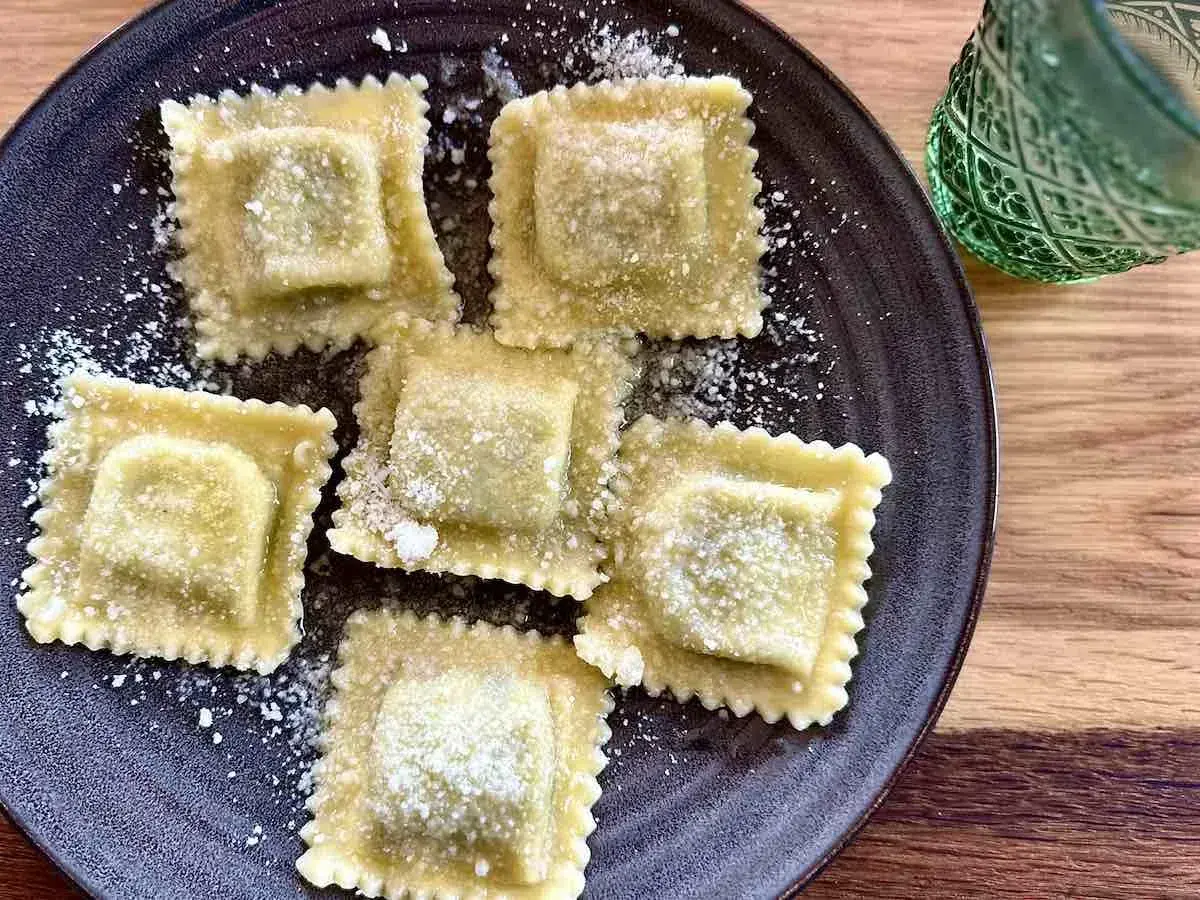 Ravioli z nadzieniem, prawdopodobnie z ricotty, posypane parmezanem. Pyszne danie, które zachęca do pytania: ricotta co to?