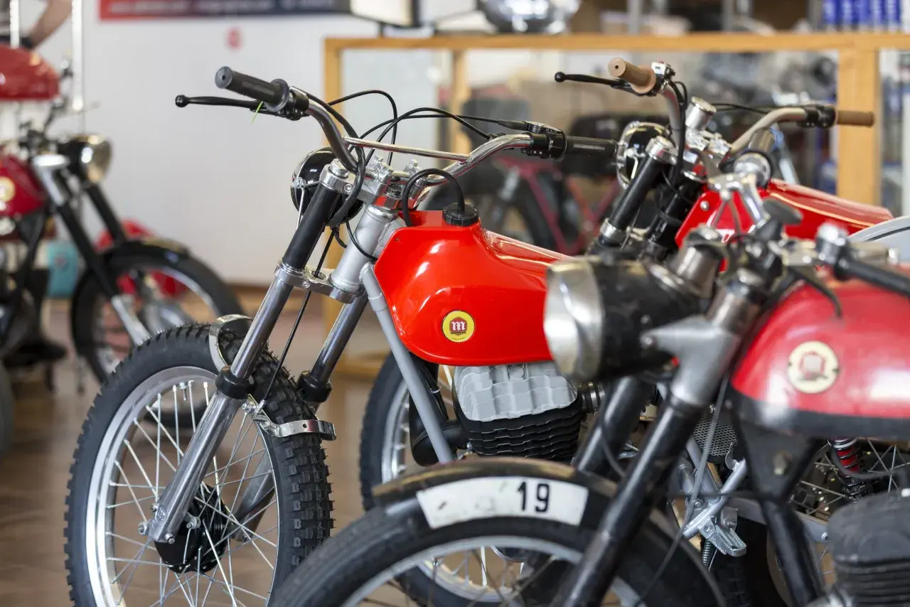 Motocicletas clásicas rojas, algunas con el número 19, que se consideran un ciclomotor.