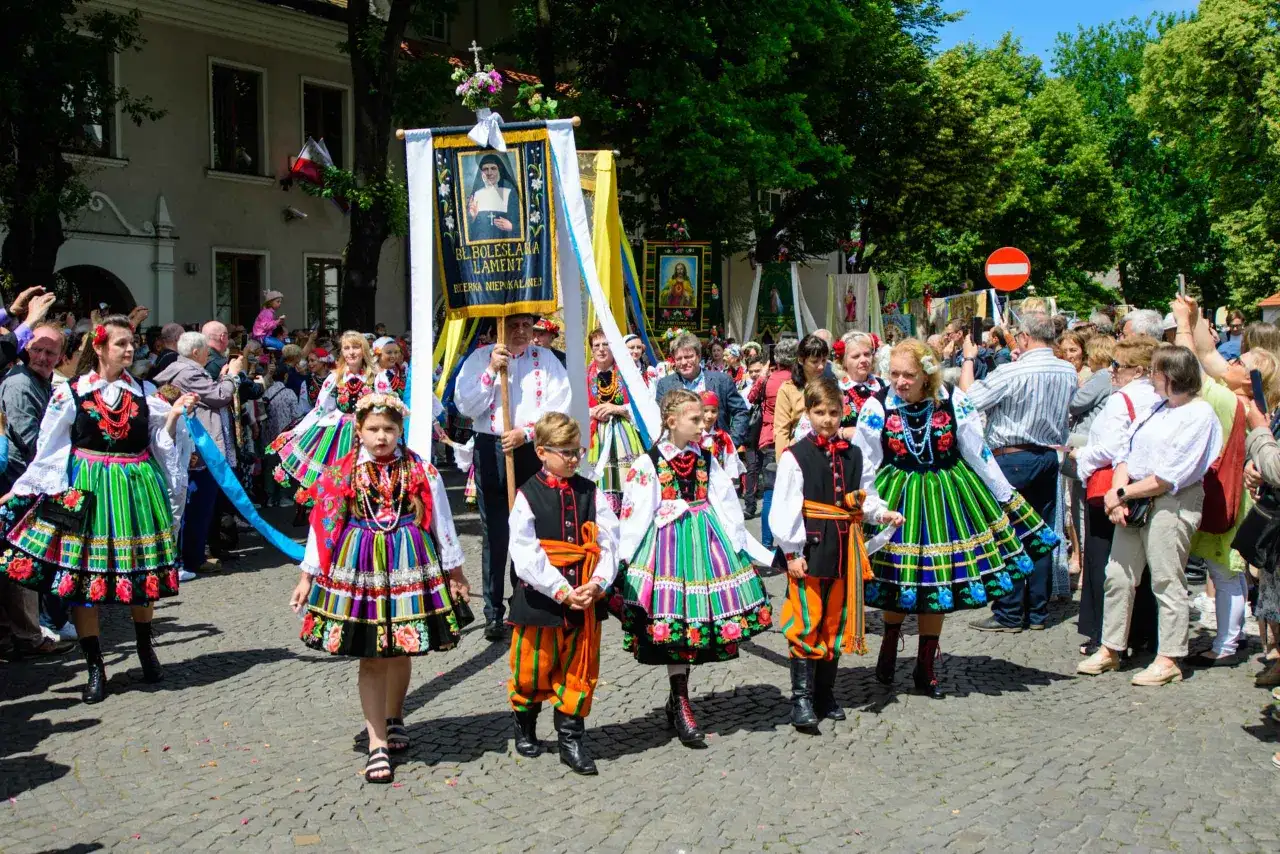 Dzieci w łowickich strojach ludowych idą w procesji Bożego Ciała. Warto uczestniczyć w procesjach Bożego Ciała w Łowiczu i okolicach, by podziwiać te barwne tradycje.