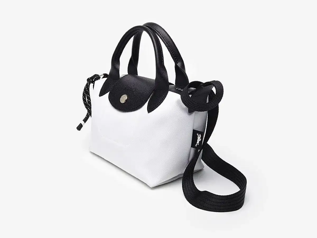 Bolso Longchamp blanco y negro, con asas de cuero y correa ajustable. Ideal para un look moderno y chic.