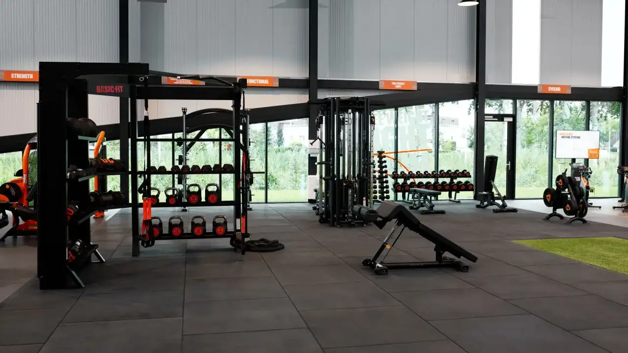 Estanterías con pesas, kettlebells y equipo de entrenamiento funcional en un gimnasio. Todo listo para tu **basic fit**.