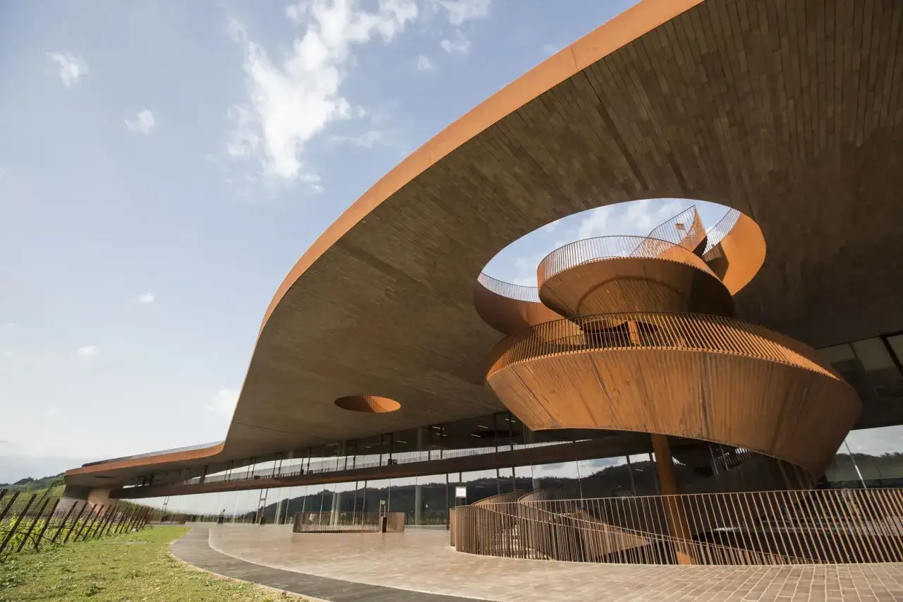Moderna architettura di cantine in Toscana, con una scala a chiocciola in corten che si snoda sotto un tetto a sbalzo.
