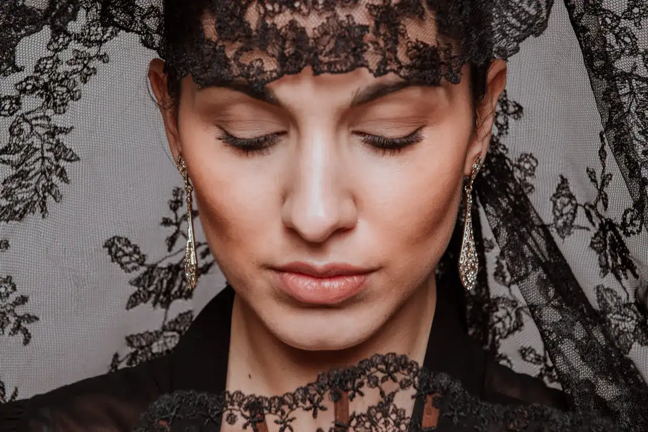 Mujer con peinados de mantilla, luciendo pendientes largos y un abanico de encaje.