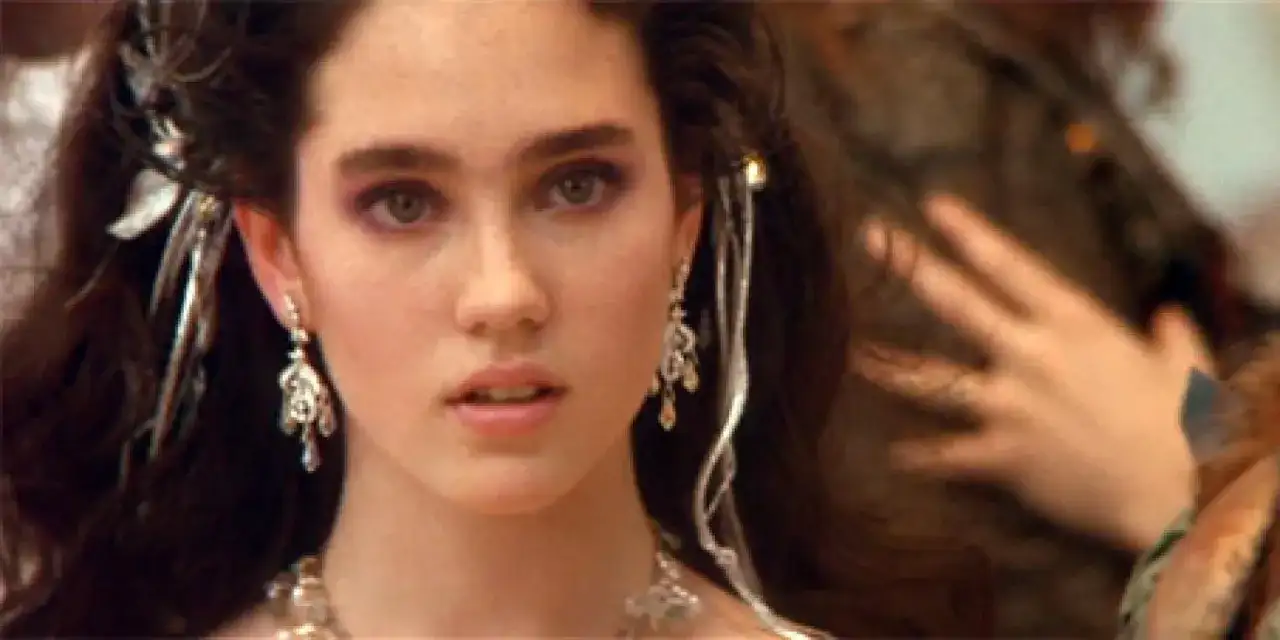 Jennifer Connelly w filmach, z burzą ciemnych włosów ozdobionych srebrnymi dodatkami i wyrazistym makijażem oczu.