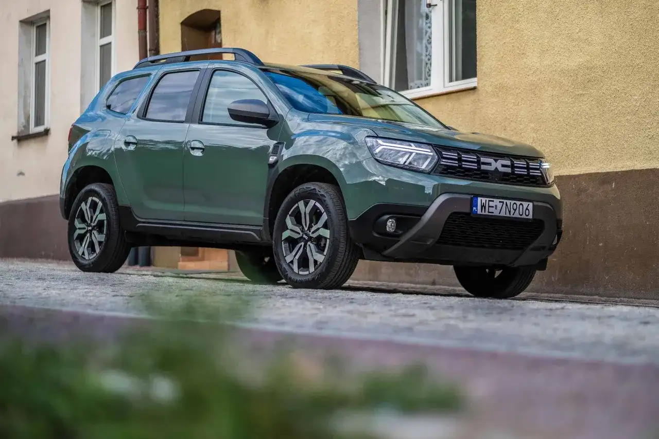 Zielony Dacia Duster na brukowanej ulicy. Wiele pozytywnych dacia duster opinie potwierdza jego wszechstronność.