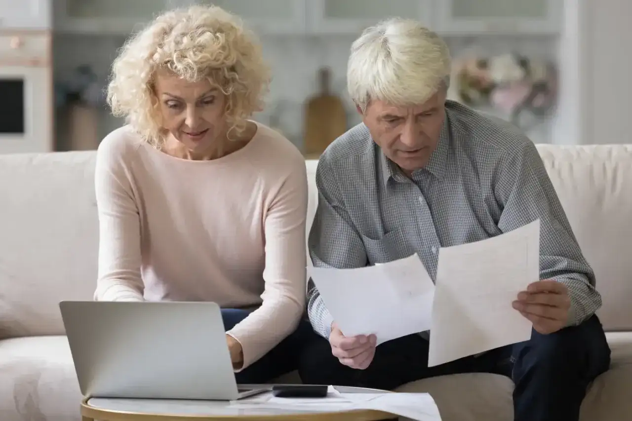 Para planuje emeryturę pomostową, analizując dokumenty i korzystając z laptopa.