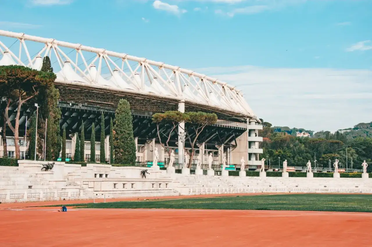 Stadion w Rzymie z rzędami rzeźb i zielenią.