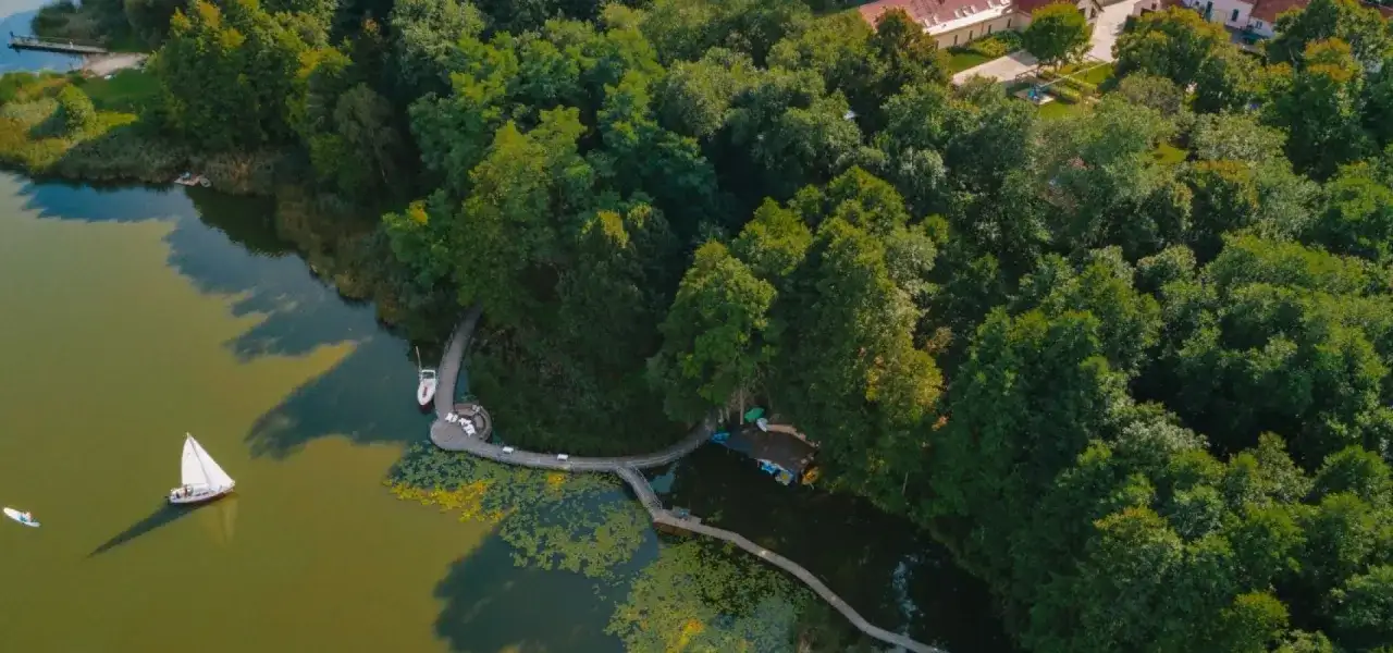 Drewniane pomosty i łódki tworzą fajne miejsca nad jeziorem, otoczone bujną zielenią.