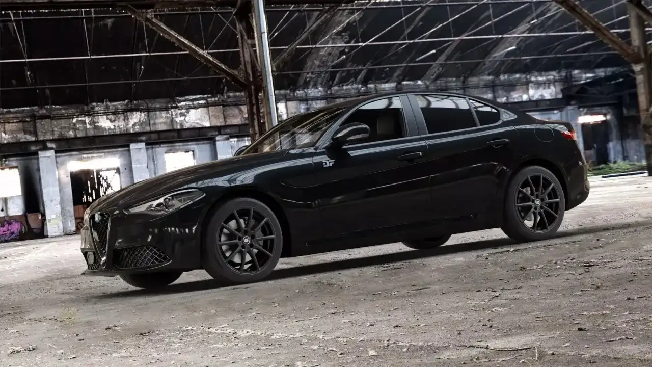 Czarny Alfa Romeo Giulia Quadrifoglio w opuszczonej hali przemysłowej.