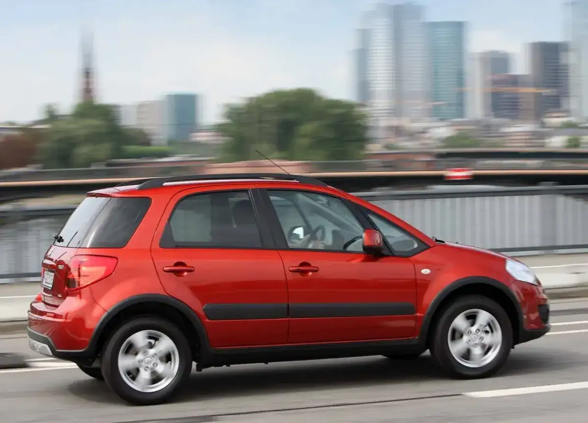 Czerwony Suzuki SX4 w ruchu miejskim. Wiele osób chwali ten model, a jego opinie są pozytywne.