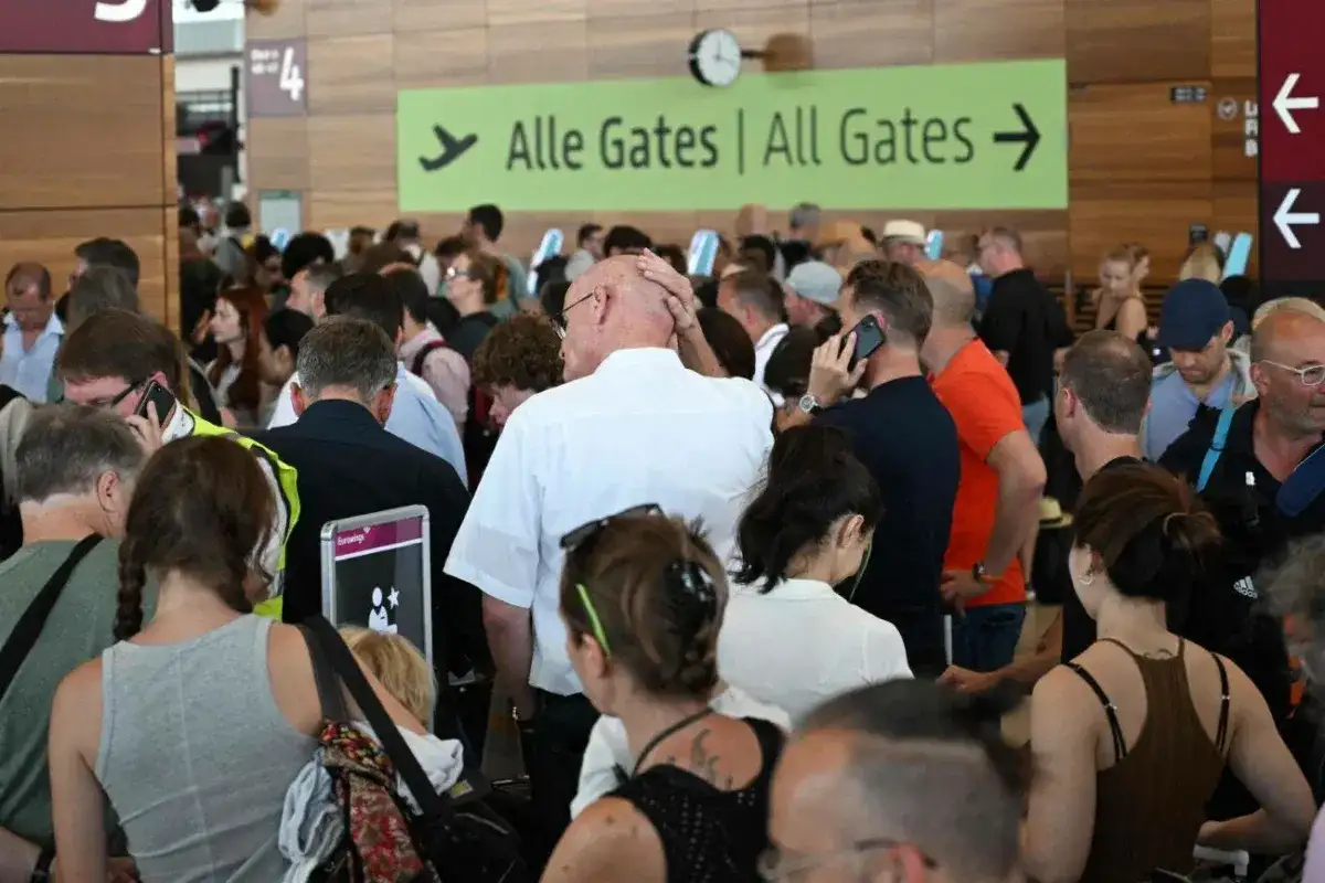 Tłum ludzi na lotnisku, znak "Alle Gates | All Gates". Czy Polacy potrzebują wizy do Wielkiej Brytanii?