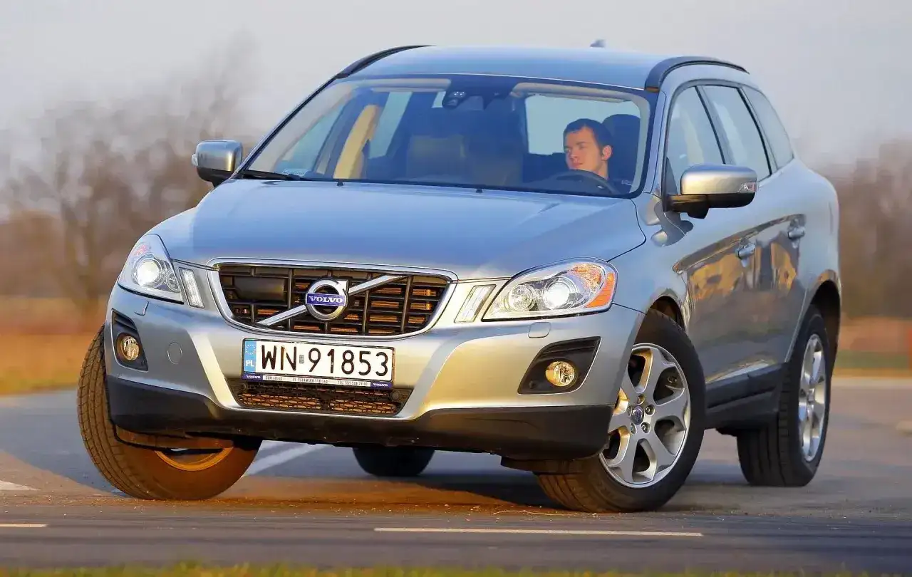 Srebrny Volvo XC60 z kierowcą na drodze. Sprawdź aktualną volvo xc60 cena i oferty.