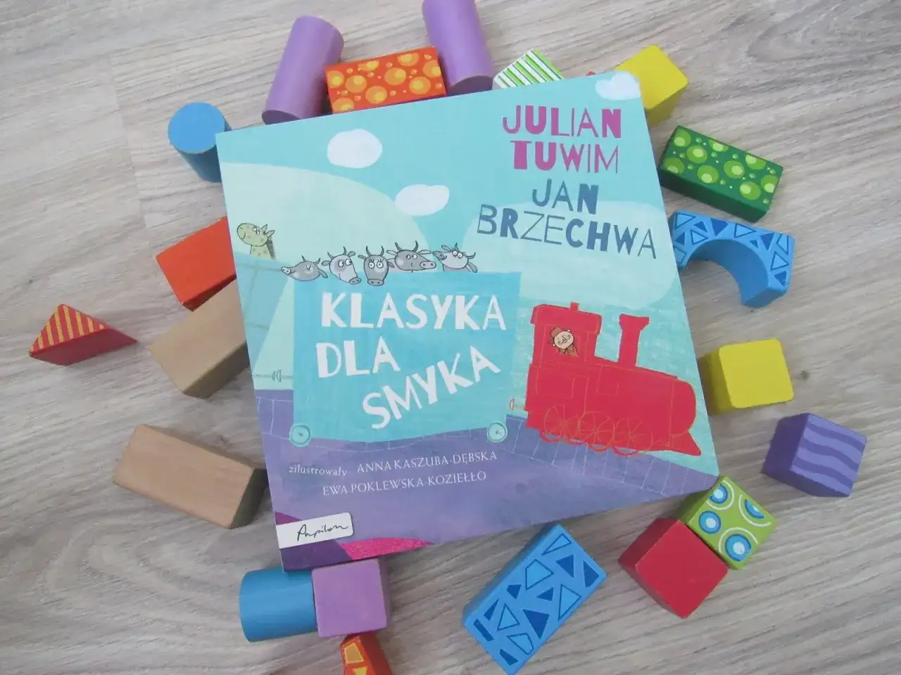 Książka "Klasyka dla smyka" z wierszami Tuwima i Brzechwy, otoczona kolorowymi klockami. Czytanie jej to jak zabawa, a nie jak szukanie karaluchów pod poduchy.