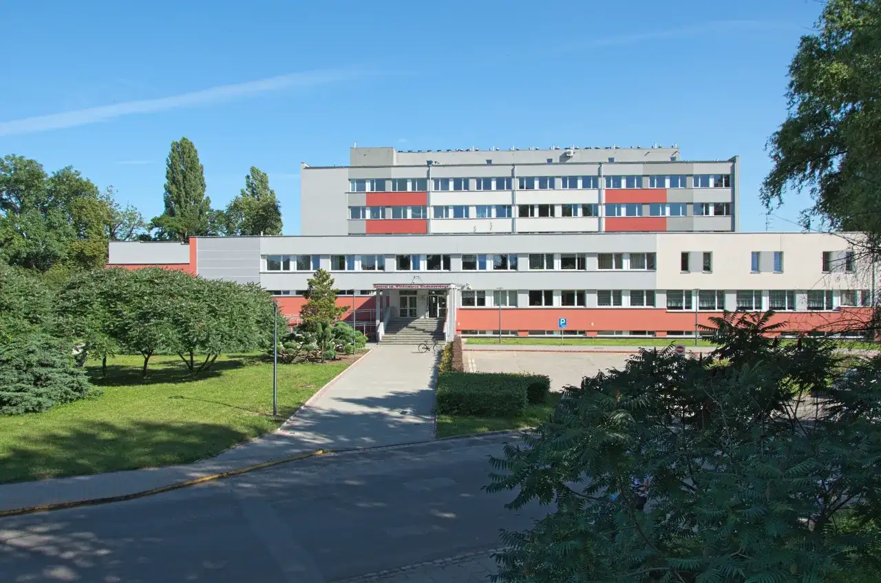 Instytut Niskich Temperatur i Badań Strukturalnych PAN we Wrocławiu. Budynek z czerwonymi i szarymi elementami, otoczony zielenią.