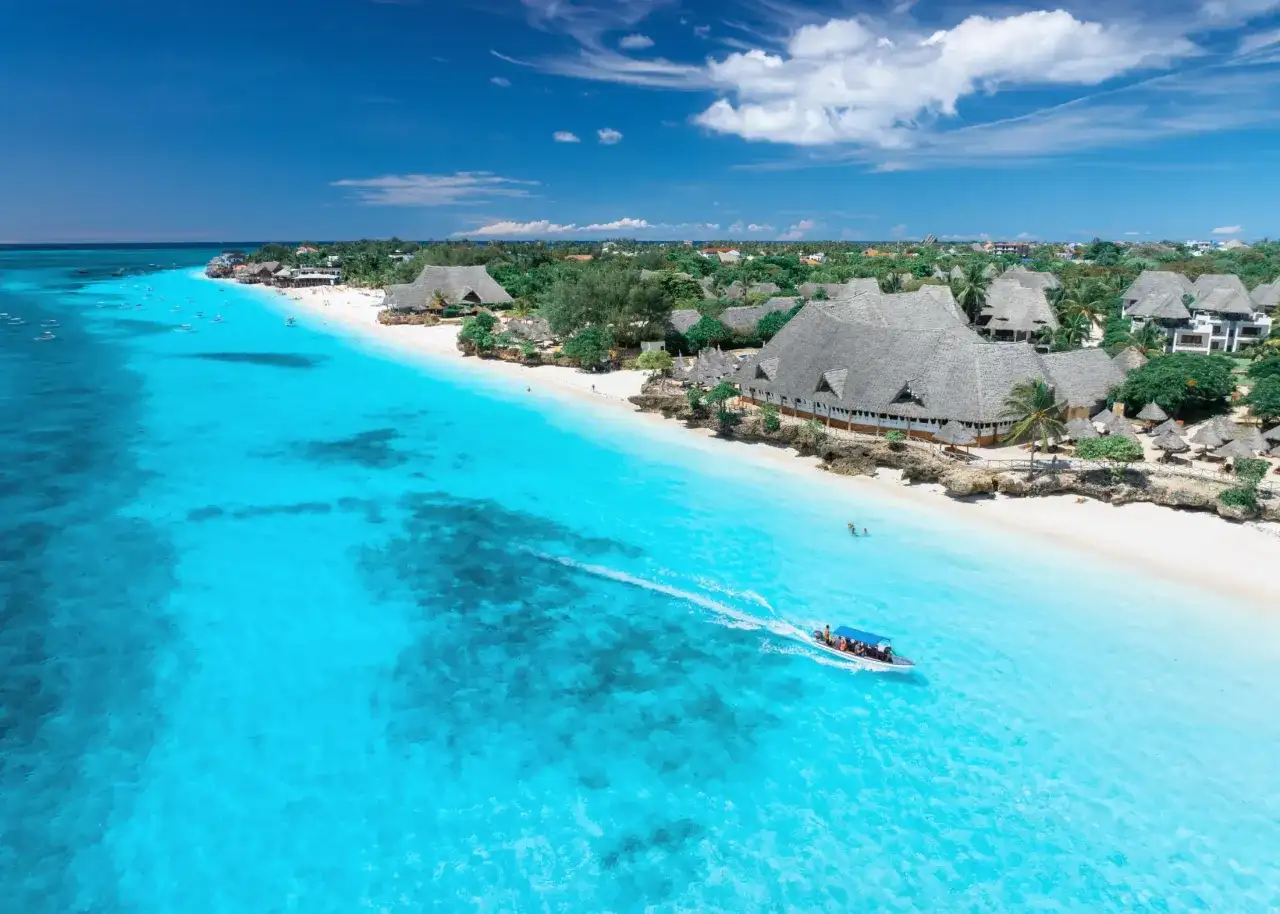 Idealny dzień, kiedy na Zanzibar. Turkusowa woda, biała plaża i łódź z turystami.