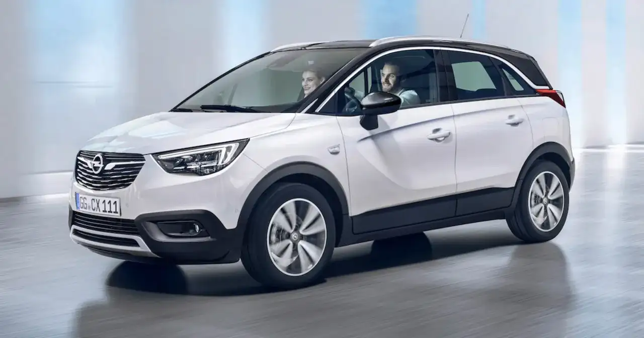 Biały Opel Crossland z parą uśmiechniętych ludzi w środku. Sprawdź atrakcyjną opel crossland cena!