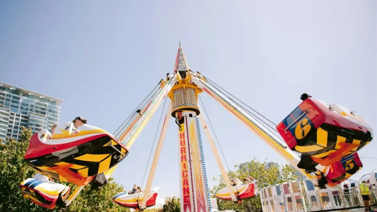 Karuzela "Hurricane" wesoło kręci się na tle błękitnego nieba, przypominając polski Disneyland.