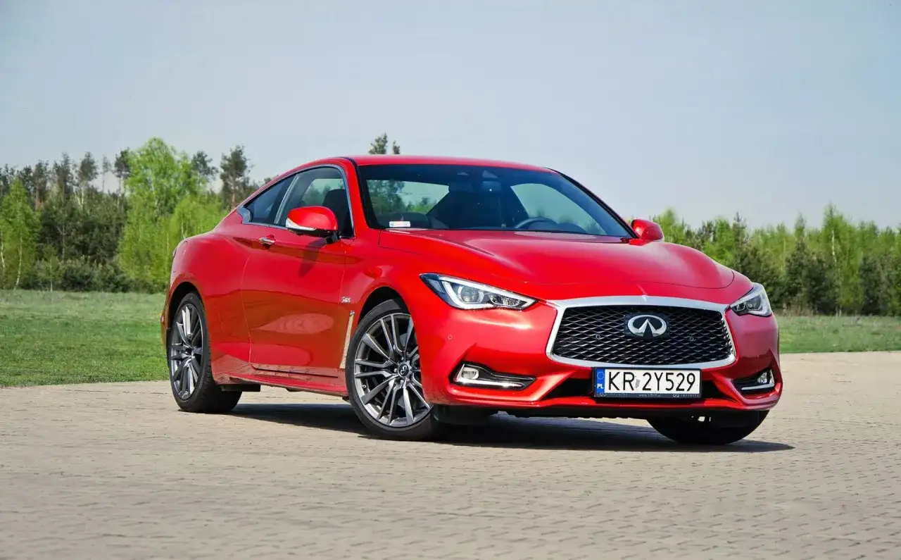 Czerwony Infiniti Q60s na tle zieleni. Eleganckie coupe gotowe do jazdy.
