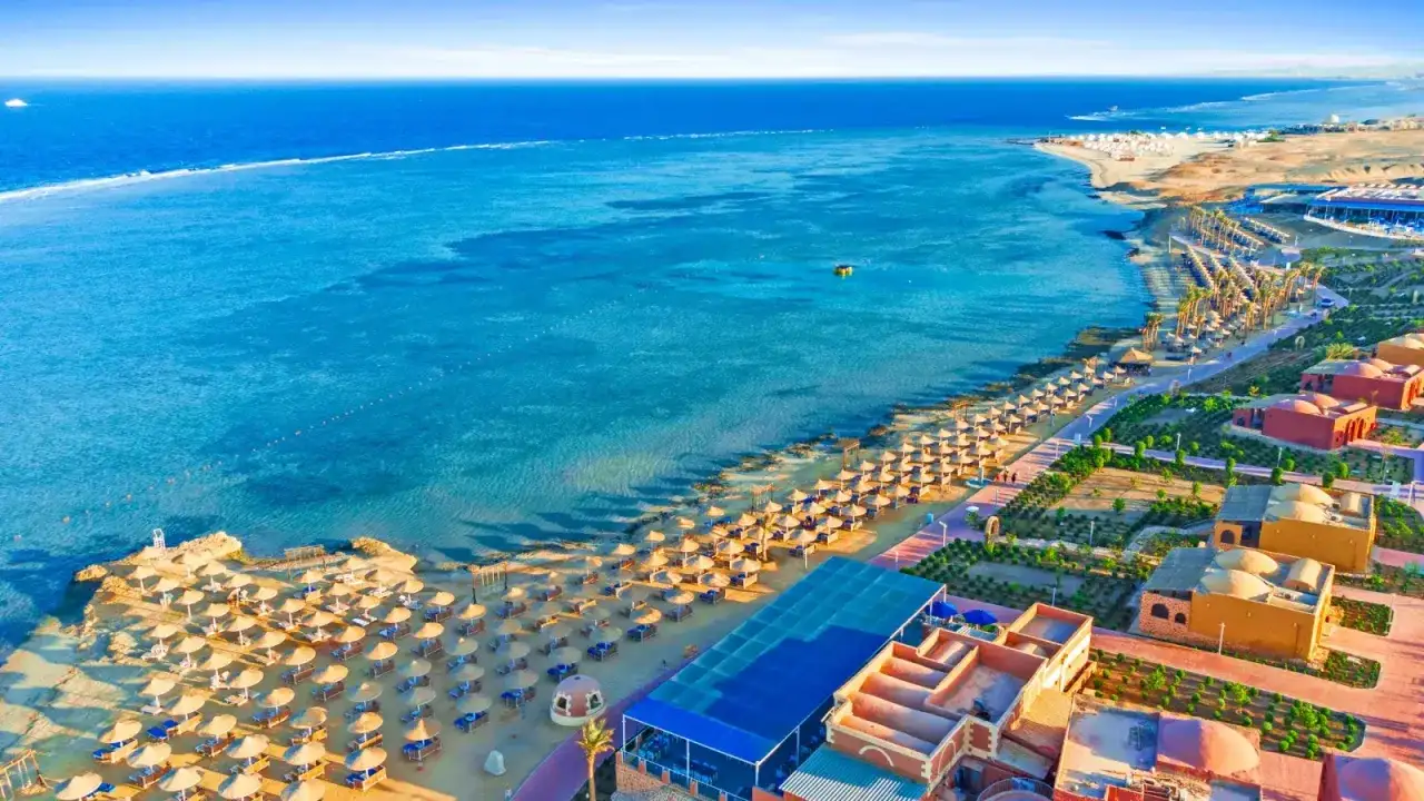 Piękna plaża z rzędami parasoli i palm, turkusowe morze i hotelowe budynki. Marsa Alam atrakcje zachwycają!