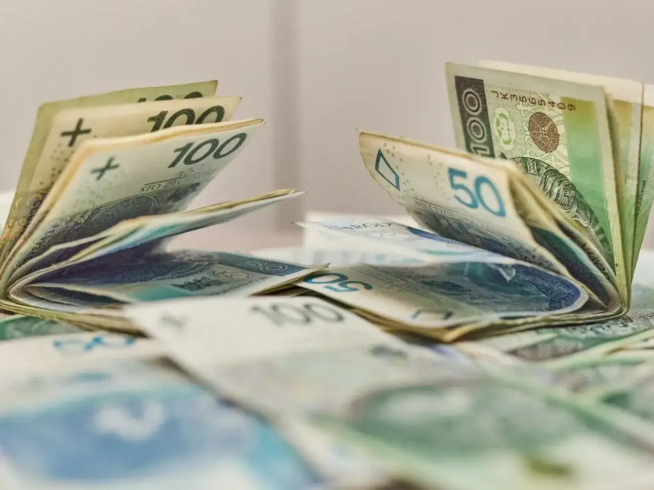 Pieniądze, banknoty 100 i 50 zł, leżące na stole. Może to być dodatek aktywizacyjny dla pracowników.
