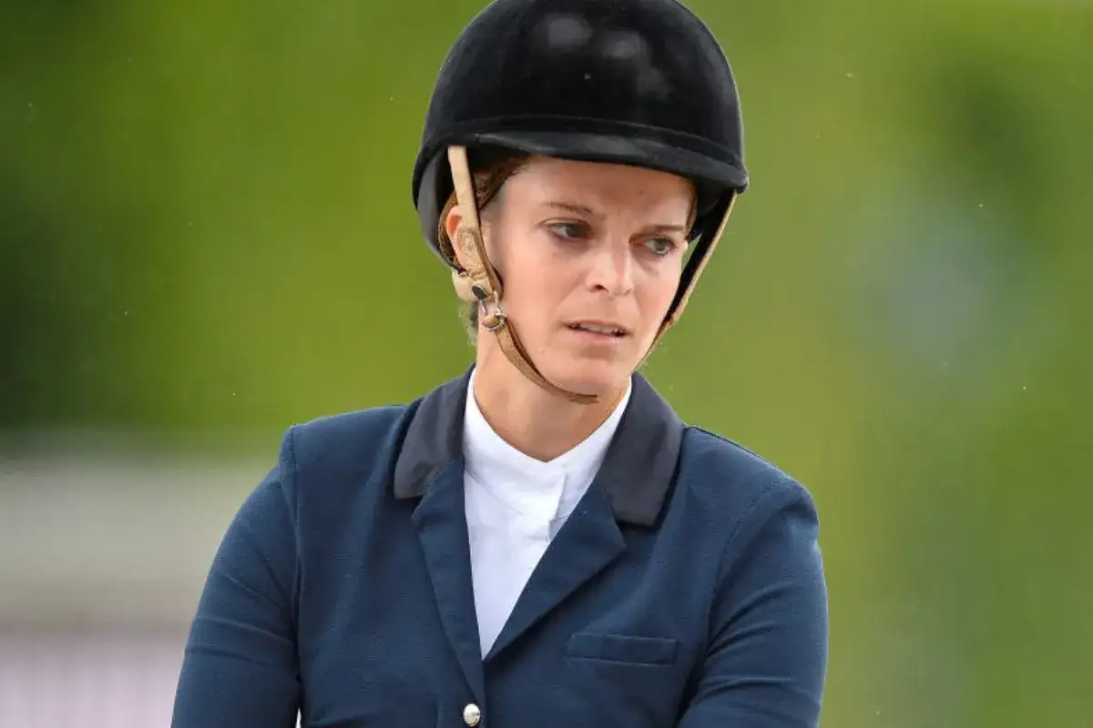 Athina Onassis w kasku i eleganckim stroju jeździeckim, skupiona na zawodach.