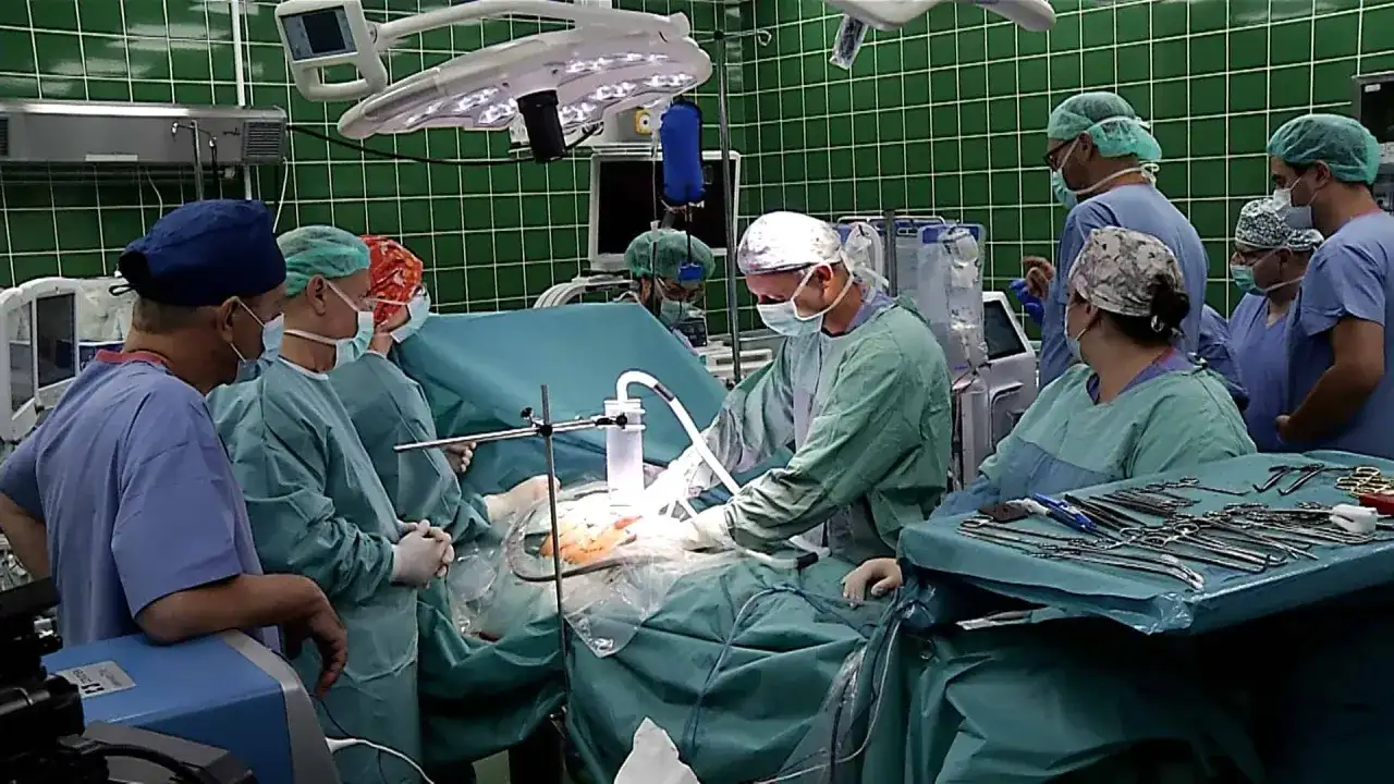 Zespół chirurgów w zielonych fartuchach i maseczkach podczas operacji.