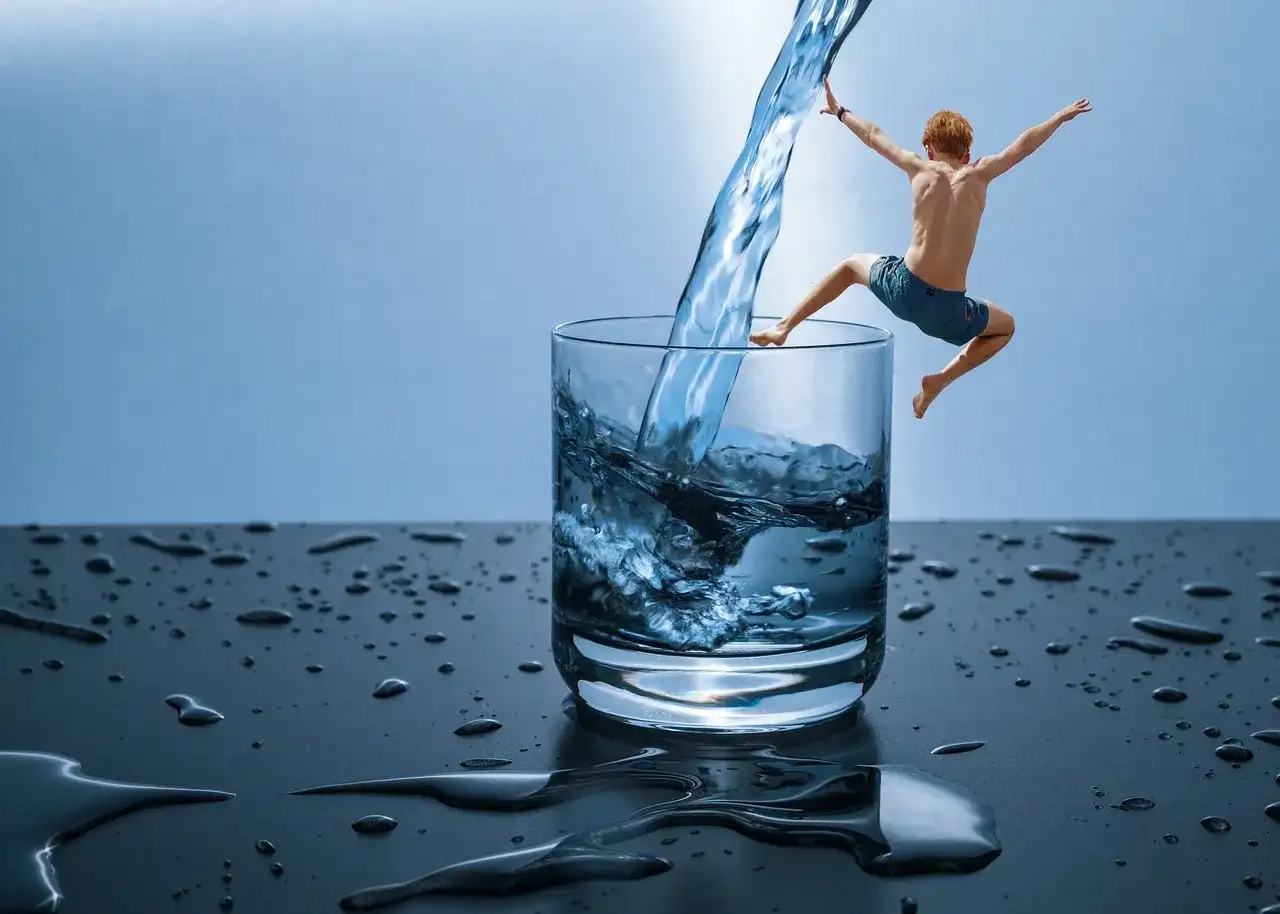 Chłopiec skacze do szklanki z wodą, jakby odkrywał, czym jest hydroterapia.