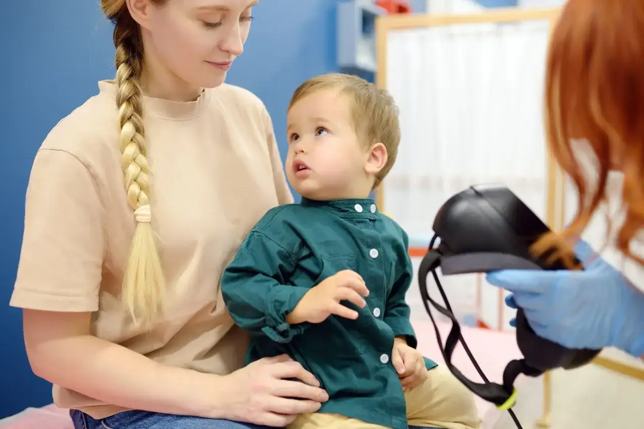 Matka z synkiem u lekarza. Dziecko patrzy z zaciekawieniem na sprzęt medyczny, a rodzicielka z troską. Czy epilepsja jest uleczalna?