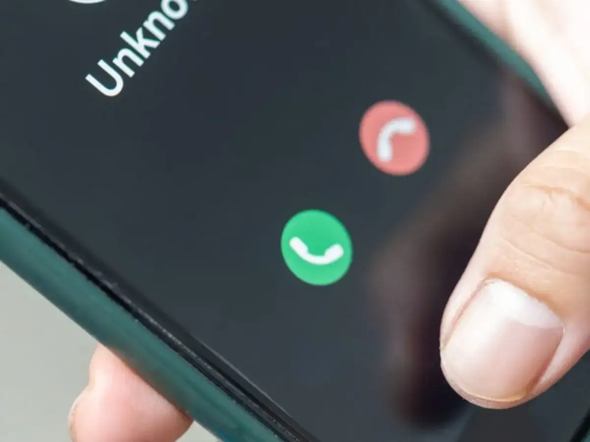 Dłoń zbliża się do ekranu telefonu, by odebrać połączenie od nieznanego numeru. Słychać lekki echo w telefonie.