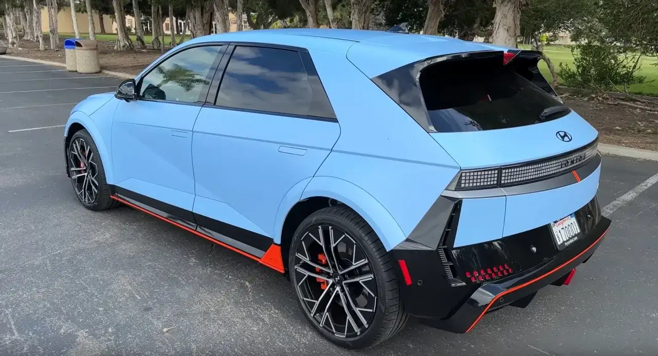 Niebieski Hyundai Ioniq 5 N z czarnymi akcentami i pomarańczowymi detalami stoi na parkingu.